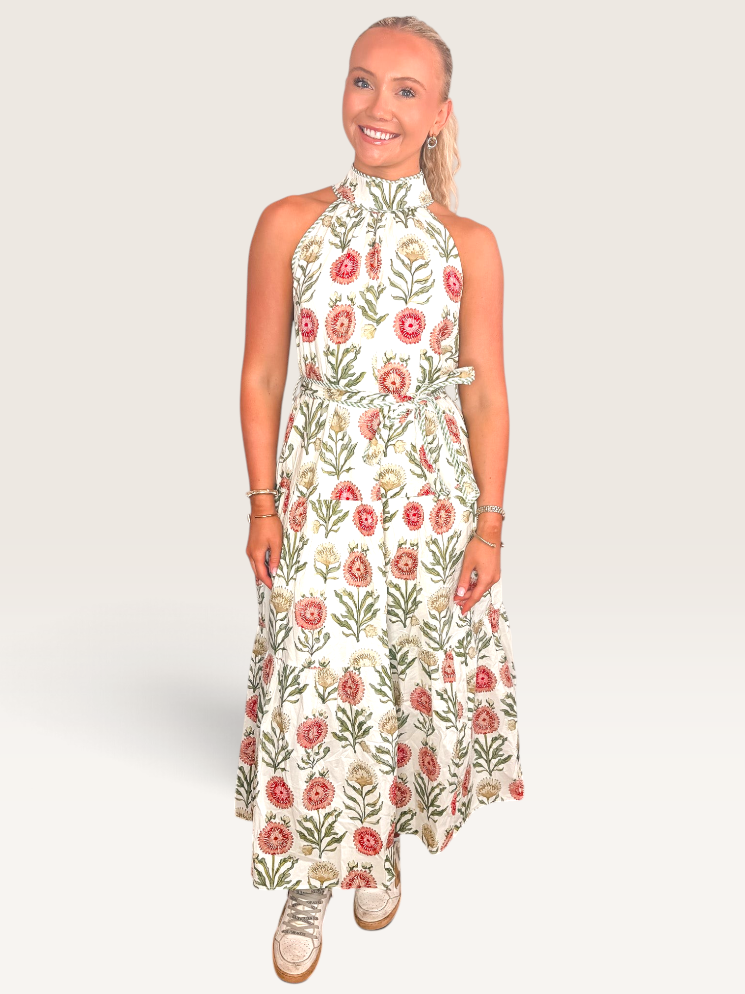Tucker Brown Zinnia floral print sleeveless maxi dress with a high halter neckline on a smiling woman