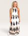 Tucker Brown Liza maxi dress with a black and cream print, halter neckline, and tie back worn by a blonde model.