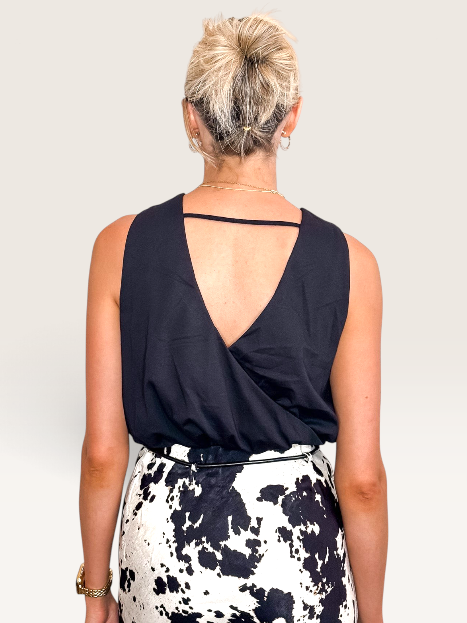 Tucker Brown black crop tank top with a V-open back design worn by a woman with blonde hair in a bun