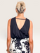 Tucker Brown black crop tank top with a V-open back design worn by a woman with blonde hair in a bun