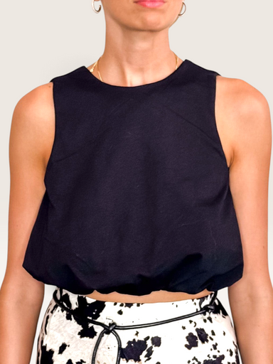 Tucker Brown black bubble crop tank top with a mock neckline worn by a model against a white wall.