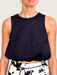 Tucker Brown black bubble crop tank top with a mock neckline worn by a model against a white wall.