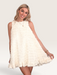 Tucker Brown white babydoll mini dress with eyelash ruffles, mock neck, and pearl buttons worn by a smiling model.