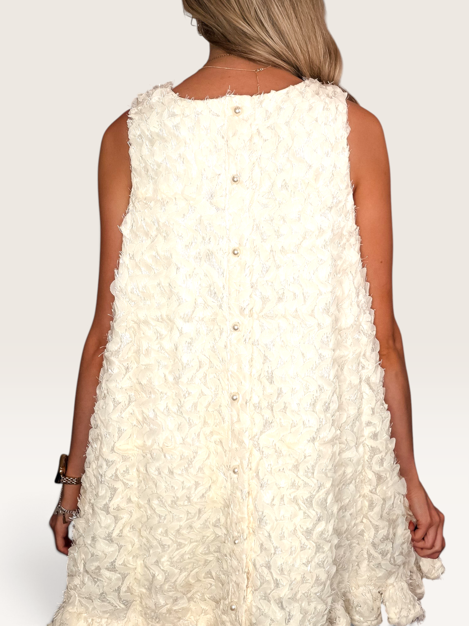Tucker Brown cream babydoll mini dress with eyelash ruffles and pearl button back closure on a model