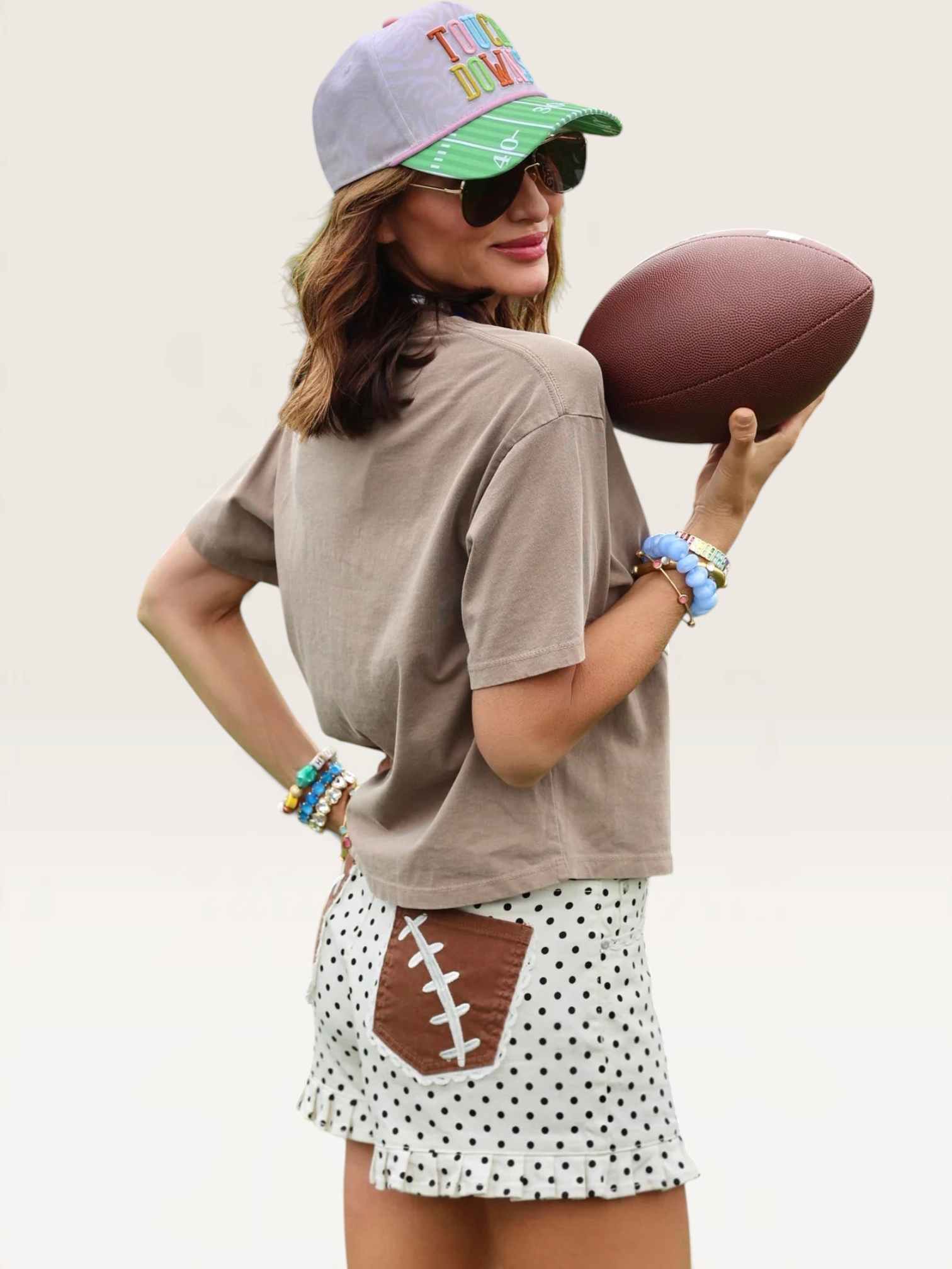 Tucker Brown high-waisted white polka dot shorts with brown football lace pockets worn on a football field