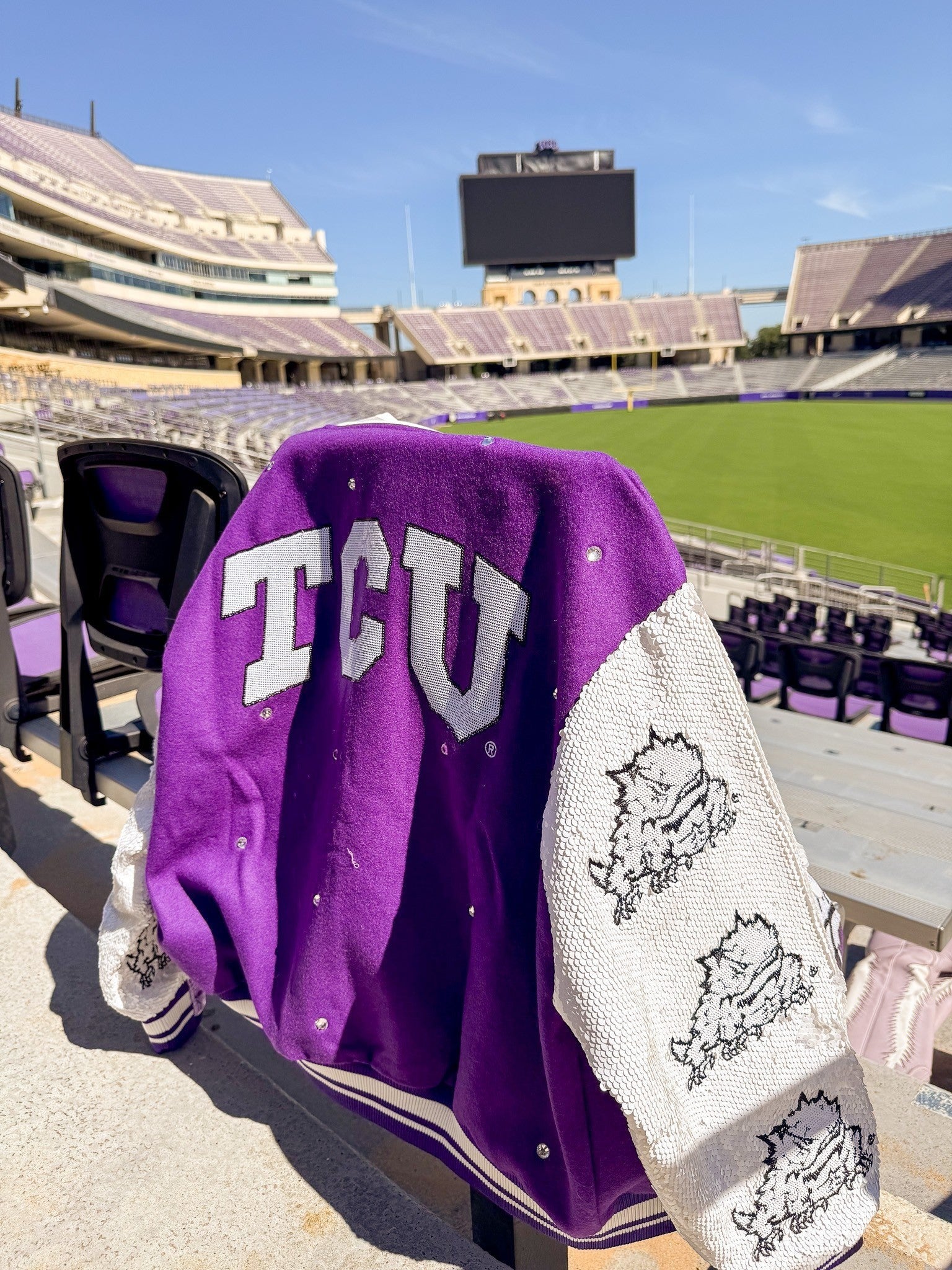 Tucker Brown TCU varsity jacket with purple body, white textured sleeves, and rhinestone accents in a stadium.
